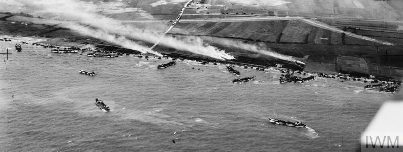 Photographie aérienne oblique de la jonction des plages King Red et King Green, zone d'assaut Gold, lors du débarquement de la 50ième Division d'infanterie, le 6 juin 1944. La batterie du Mont Fleury (WN 35a) et un fossé antichar sont visibles devant le village de Ver-sur-Mer.